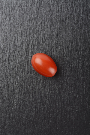 Tomatoes on background of black slate plateの写真素材