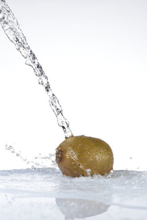 Water falling on a kiwi on white backgroundの写真素材
