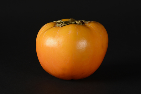 One persimmon on black backgroundの写真素材