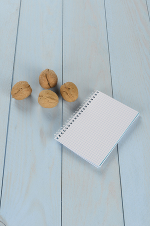 Walnuts and notepad on blue wooden background, blank notebookの写真素材