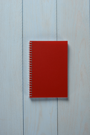 Red notebook on blue wooden background, conceptの写真素材