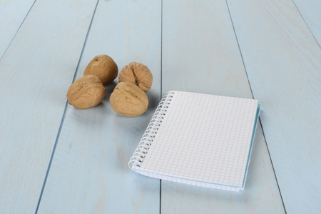 Walnuts and notepad on blue wooden background, blank notebookの写真素材