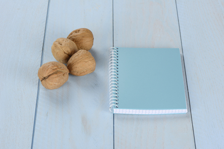 Walnuts and notepad on blue wooden background, blank notebookの写真素材