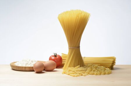 Raw pasta spaghetti, tagliatelle, penne and elbows, on wood backgroundの写真素材
