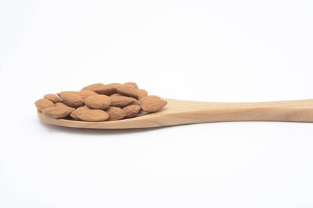 Natural almonds in a wooden spoon on a white backgroundの写真素材