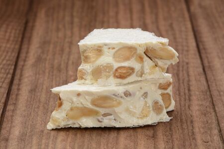 Hard nougat on wooden background, cut into piecesの写真素材
