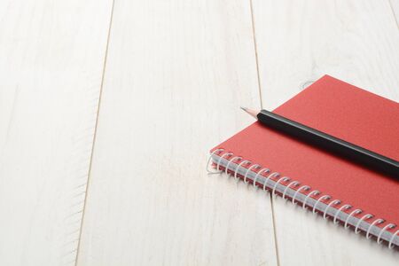 Notebook and pencil on white wooden background, closed bookの写真素材