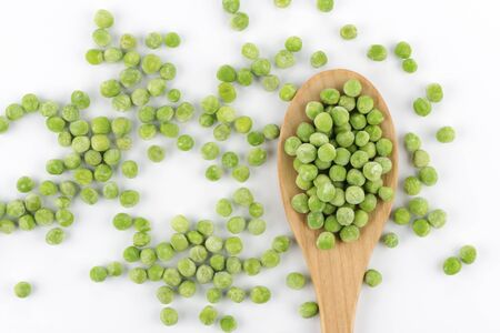 Frozen peas and a wooden spoon on white backgroundの写真素材