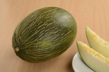 Open melon and a split slice on a plate on the tableの写真素材