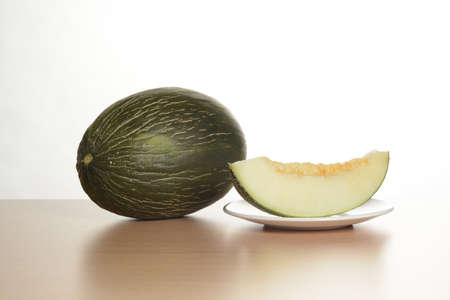 Open melon and a split slice on a plate on the tableの写真素材