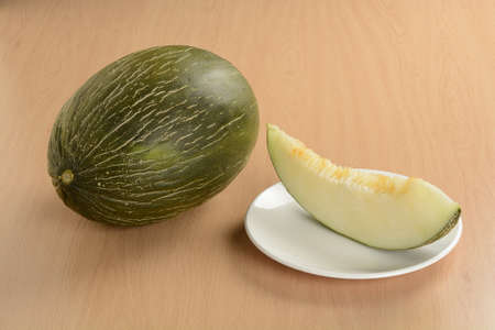 Open melon and a split slice on a plate on the tableの写真素材
