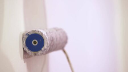 Young asian happy woman painting interior wall with paint roller in new house.の写真素材
