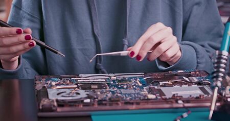 Young woman engineer is soldering microcircuit for droid in office working alone indoors using modern equipment. People, occupation and technology concept.の写真素材