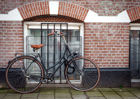 Vintage bicycle against an old house facade with an ochre stucco wall and a dark green wooden entrance door in the historic centerの写真素材