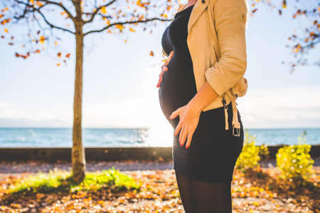 Pregnant woman standing outdoors in a green backgroundの写真素材
