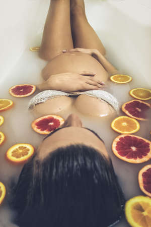 Young pregnant woman taking a bath,, containg orange sliceの写真素材