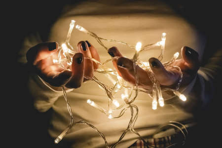 hands holding string of lights in the dark to make a wish.の写真素材