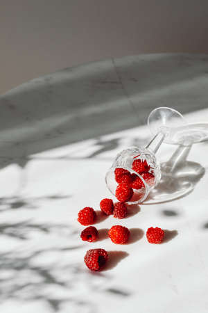 Fresh raspberries on a white floor fallen from glass on white background.の写真素材