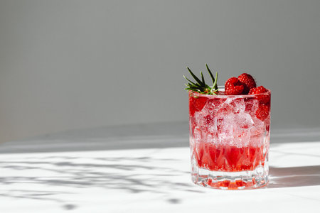 Refreshing alcoholic summer cocktail with raspberry liqueur and lemon. In white background