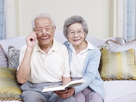 senior asian couple reading a book together at home の写真素材