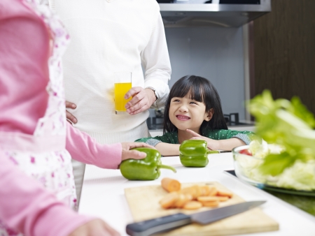 little asian girl talking to parents and smiling in kitchen の写真素材