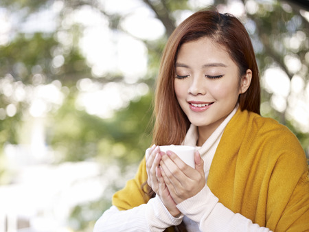 young woman holding coffee cup smiling の写真素材