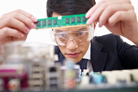 young asian man fixing computer with protective eyewear 