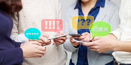hands of a group of young people playing with cellphones together.
