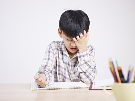 10 year-old asian elementary schoolboy appears to be frustrated while doing homework.の写真素材
