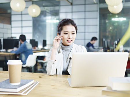 young asian business executive sitting at desk in office working using laptop computer.の写真素材