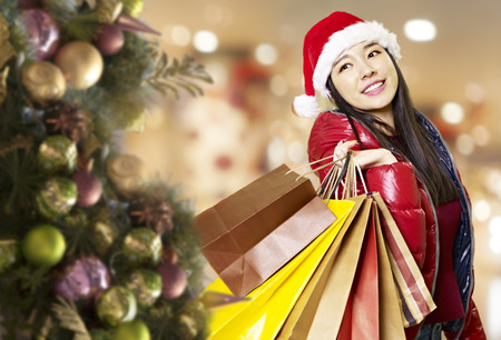 young asian woman carrying paper bags on shoulder during christmas shopping, happy and smiling.の写真素材
