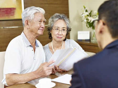 senior asian couple appear to be skeptical after reading a proposalの写真素材