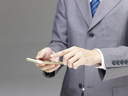 businessman using a mobile phone with finger pointing at the screen, gray background.の写真素材
