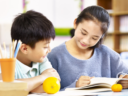 asian elementary school girl and schoolboy studying together in classroom.の写真素材