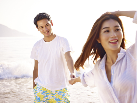 young loving and happy asian couple holding hands on beach.の写真素材