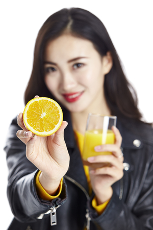 young asian woman hold a half of an orange and a glass of orange juice, isolated on white background.の写真素材