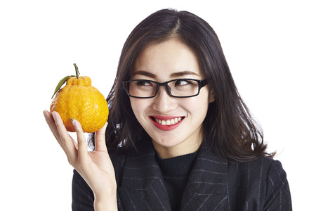 young asian businessman holding an ugli fruit, happy and smiling, studio shot, isolated on white background.の写真素材