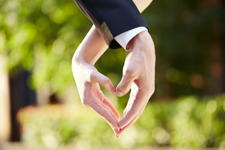 close-up shot of hands of a loving couple forming a heart shape.の写真素材