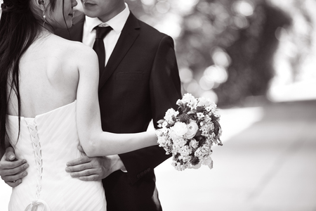 asian wedding couple hugging each other, focus on the bouquet, black and white.の写真素材