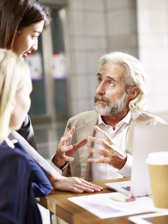 caucasian european senior executive talking to two business women in office.の写真素材