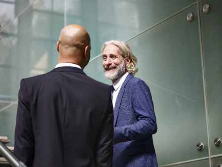 caucasian and latino corporate executives having a conversation while ascending stairs in modern office building.の写真素材