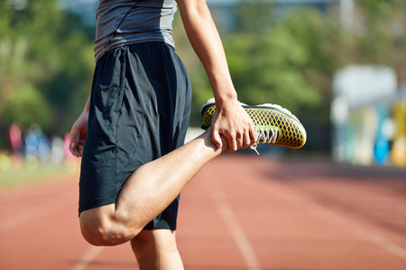 young asian man  athlete warming up stretching legs on track.