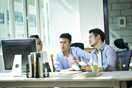 three young asian corporate executives working together discussing business plan in office.の写真素材