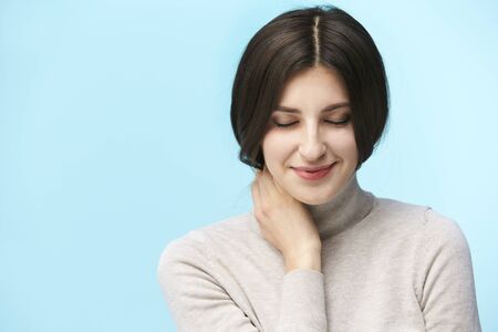 portrait of a beautiful young caucasian woman, happy and smiling, eyes closed, isolated on blue backgroundの写真素材