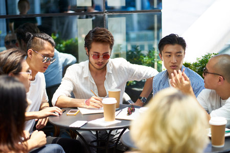 young asian college students having a group discussion at outdoor coffee shop