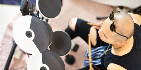 high angle view of a young asian drummer percussionist beating electronic drumsの写真素材