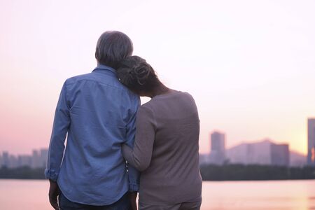 rear view of asian old couple looking at city skyline across riverの写真素材