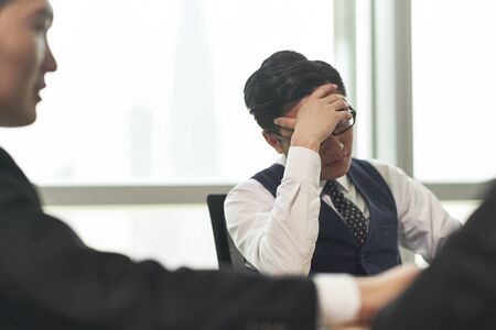 asian business man looking tired and frustrated during meeting in officeの写真素材