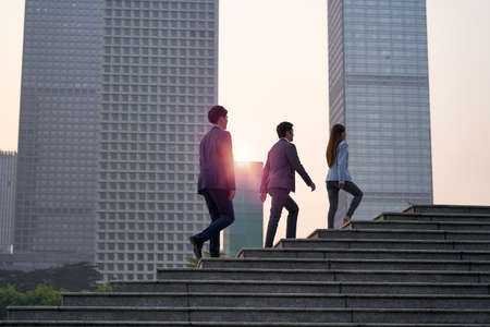 team of three asian corporate executives walking in downtown financial districtの写真素材