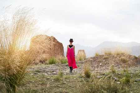 asian woman in red dress walking in a deserted historical site in morning sunlight
